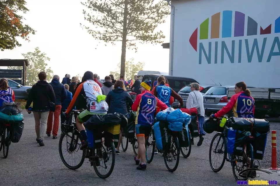 Rowerzyści NINIWA Team prowadzący rowery na tle budynku Oblackiego Centrum Młodzieży NINIWA w lublinieckim Kokotku